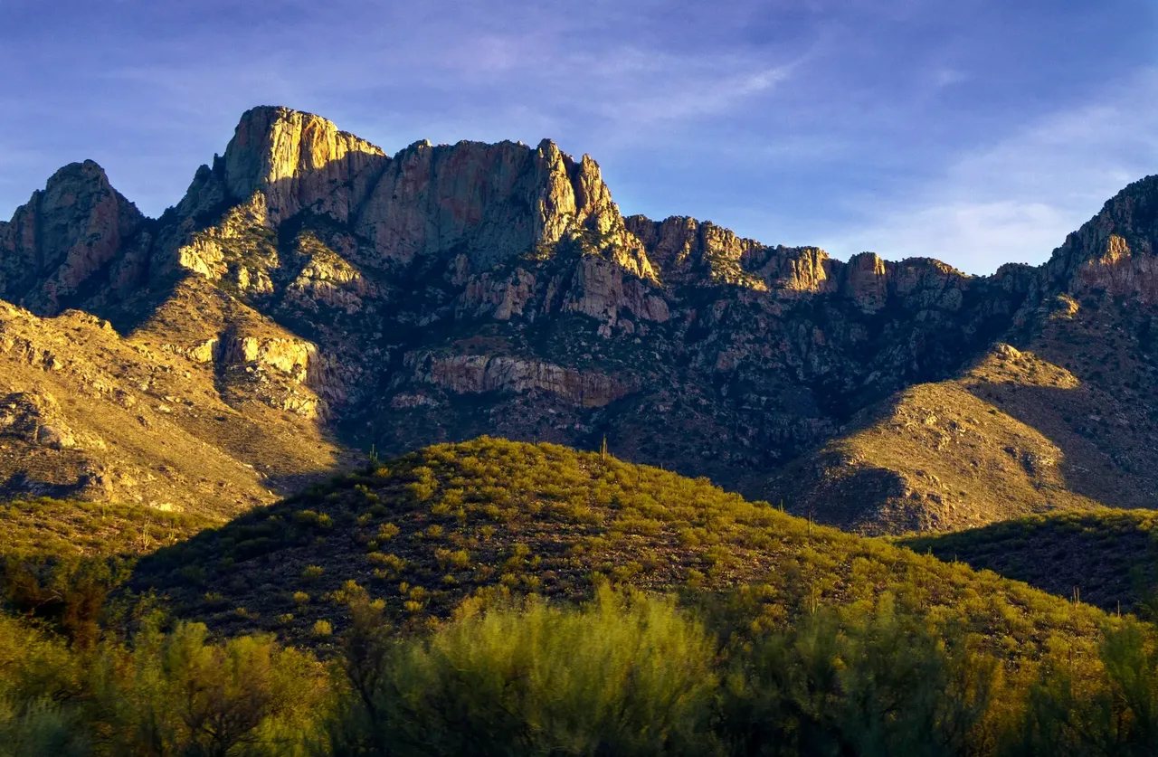 Mountains glowing in late-afternoon light over green desert foothills