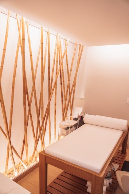 A calm treatment room at Zentelle: a white-draped massage table beside a wall of tall natural bamboo
